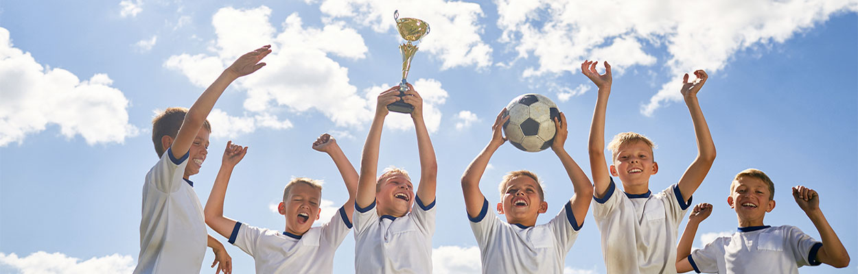 kids on soccer team celebrating holding trophy